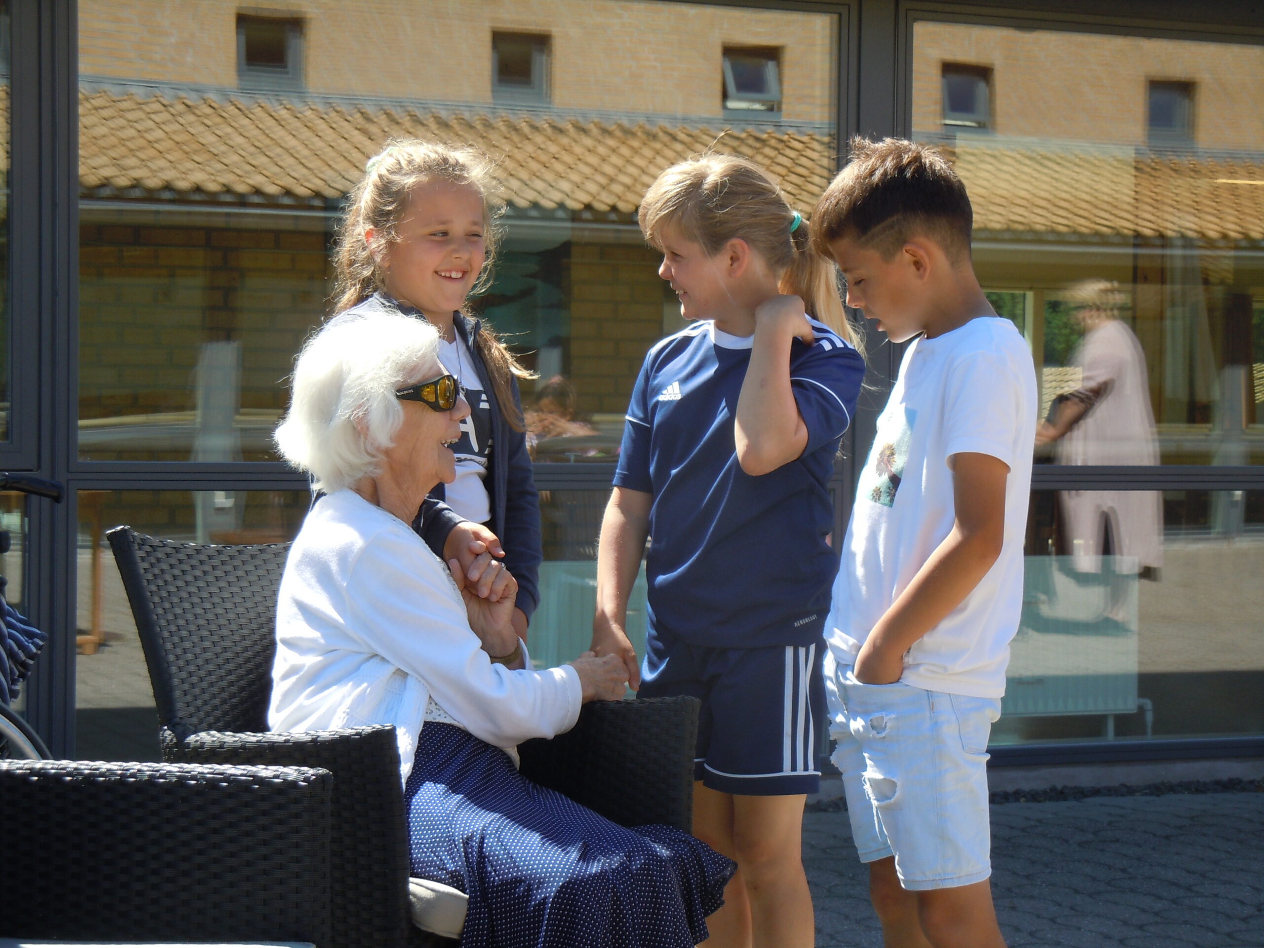 Billede af børn der snakker med en blind ældre dame