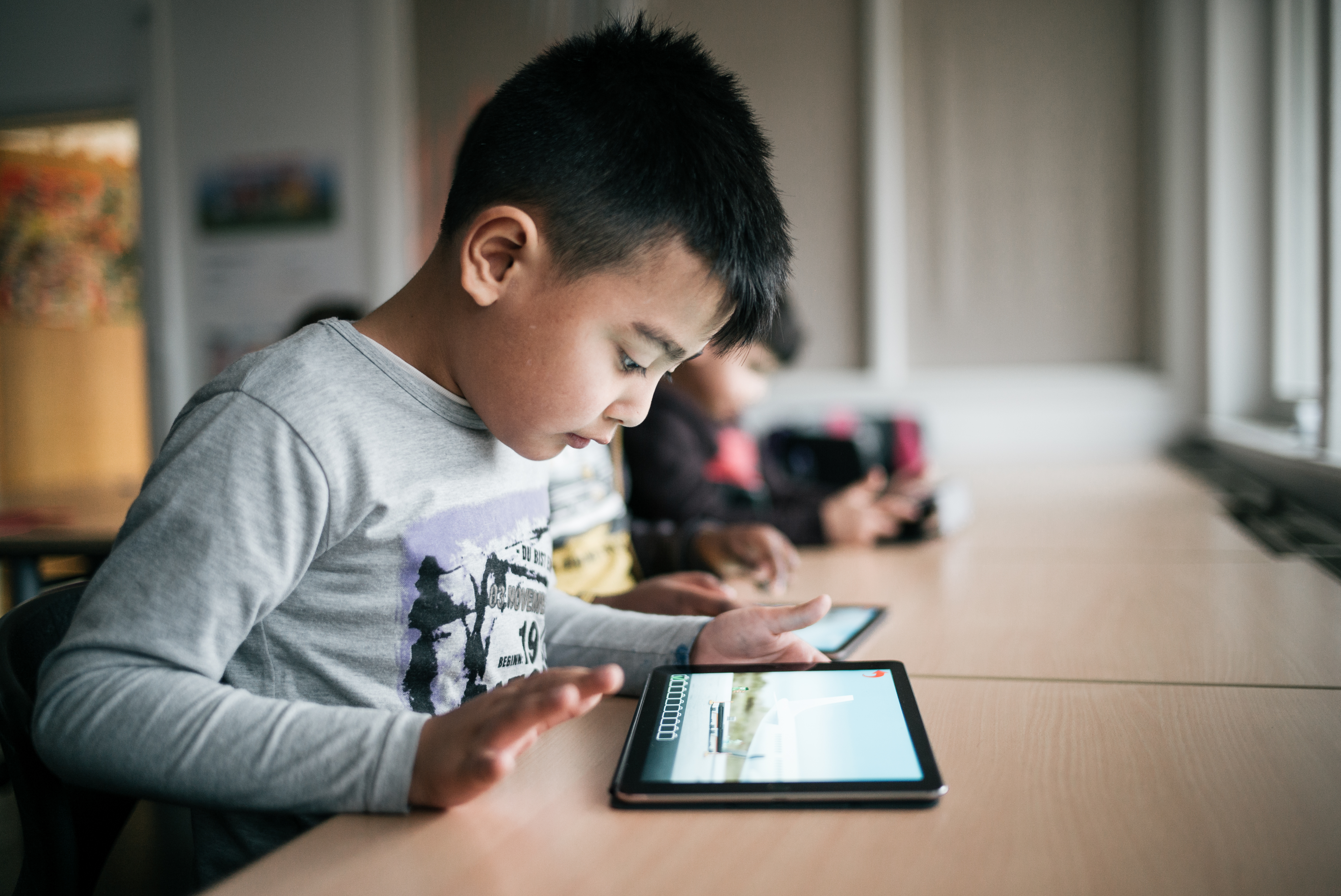 Billede af et barn der sidder ved et bord med en iPad