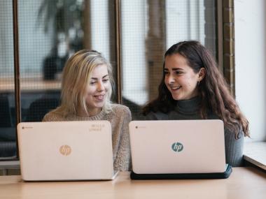 Billede af 2 piger der sidder foran deres bærbar computere